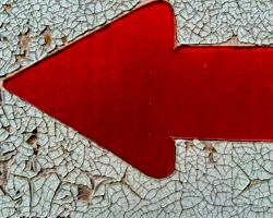 The crackled paint of a weathered road sign creates a textured abstract in red and white.