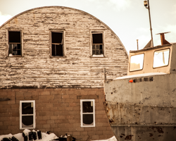 A fishing boat has come to rest next to the fishing shed that it served for years.