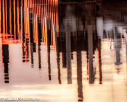 Sunset pinks and reds highlight a pier in the watery reflections of Green Bay.