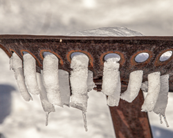 An iron seat where someone farmer once sat now spends its idle time extruding fresh snow into pasta shapes.