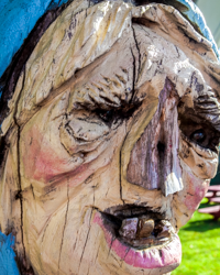 A carved wooden statue of a hag offers passers-by a toothy smile.